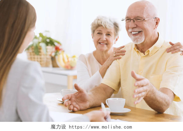坐在餐桌前和保险代理人交谈的一对老夫妇晚年幸福微笑的老人